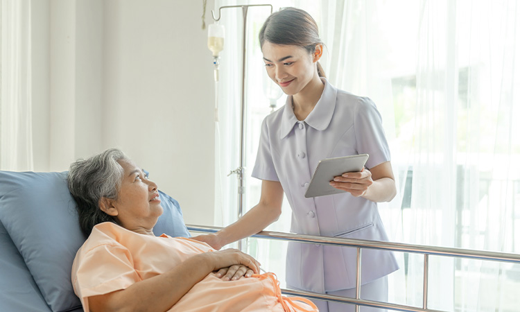 Caregiving nurse assisting an elderly lady on a hospital bed