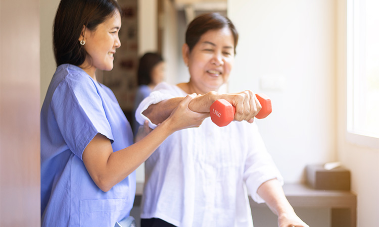 Physiotherapist assisting an elderly man with weightlifting exercises.