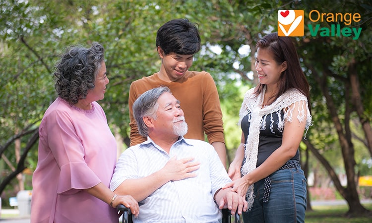 Multi-generational family visiting elderly loved one outdoors