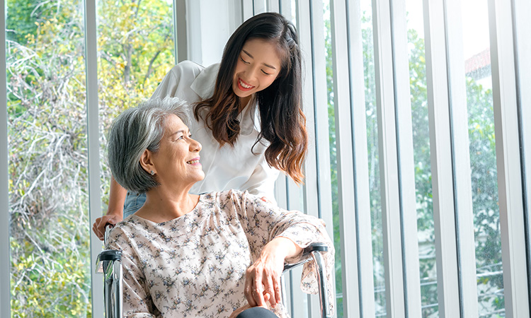 Woman smiling with elderly loved one in wheelchair