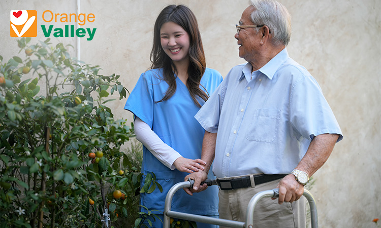 Nurse supporting an elderly man with a walker.